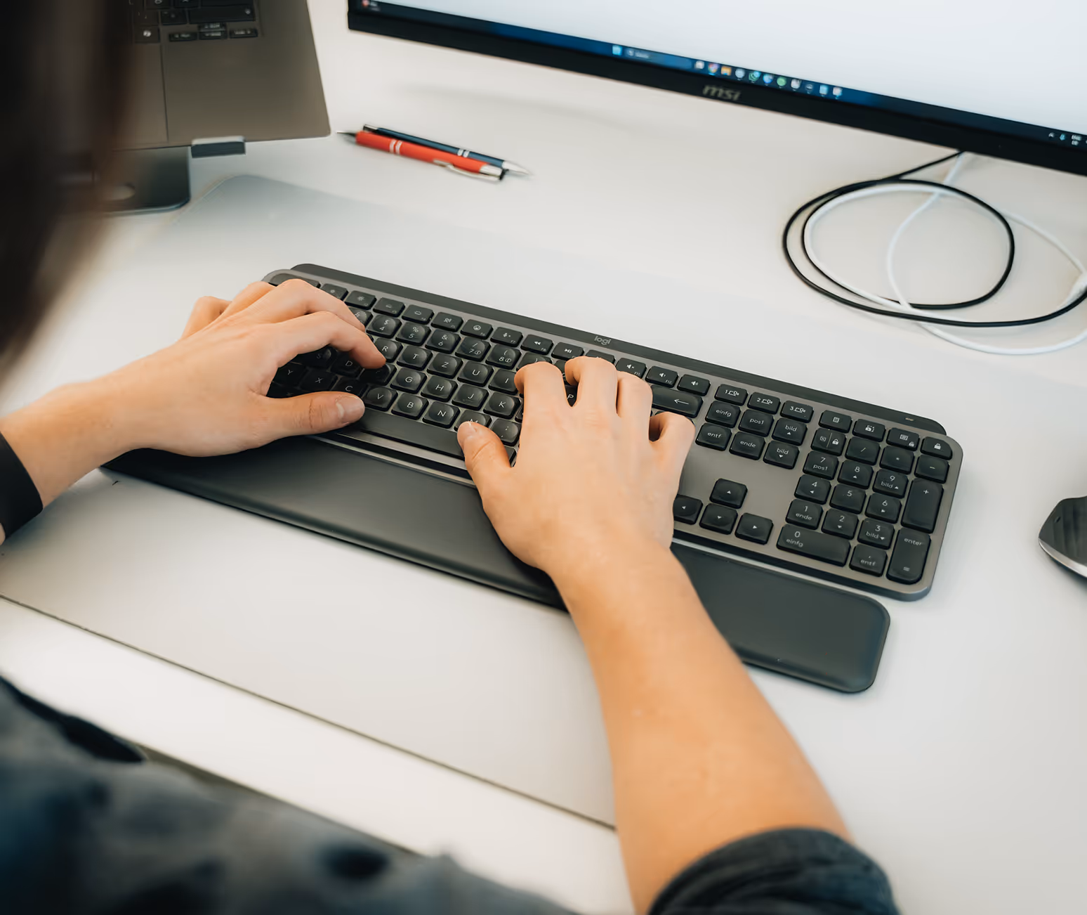Hände auf einer Tastatur am FourLead-Arbeitsplatz